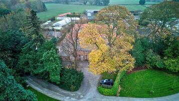 Luchtbeeld van een woongebied met een opvallend huis, omringd door weelderige begroeiing en een heldere weg.