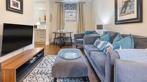 A modern living room with a flat-screen TV, grey sofa, and a dining area with a table and chairs. - No. 4 - Oak Tree Cottage - Pass the Keys (Middlethorpe)