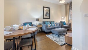 A modern living room with a wooden dining table, grey sofas, and a patterned rug. - No. 4 - Oak Tree Cottage - Pass the Keys (Middlethorpe)