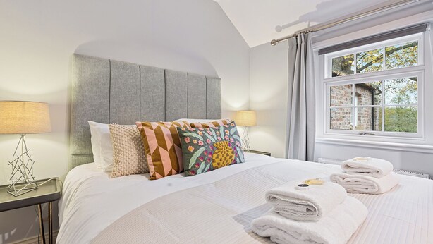 A neatly made bed with a white comforter, pillows, and folded towels. - No. 4 - Oak Tree Cottage - Pass the Keys (Middlethorpe)