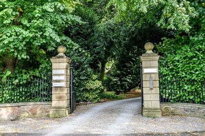 A gated entrance with stone pillars and a sign listing names. - No. 5 - Chestnut Cottage - Pass the Keys (Middlethorpe)
