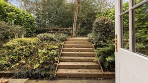 A wooden staircase leading to a building, surrounded by lush greenery and trees. - No. 6 - Wisteria Cottage - Pass the Keys (Middlethorpe)