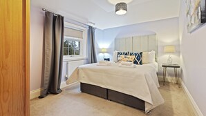 A bedroom with a bed, a window with curtains, a bedside table with a lamp, and a headboard. - No. 6 - Wisteria Cottage - Pass the Keys (Middlethorpe)