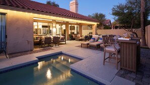 A poolside area with a covered patio, outdoor seating, and a pool.