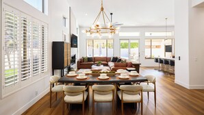 A spacious dining area with a large table set for six, surrounded by six chairs.