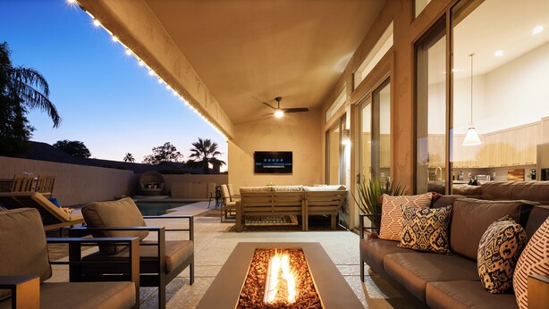 An outdoor living area with a fire feature, seating, and a view of the kitchen.