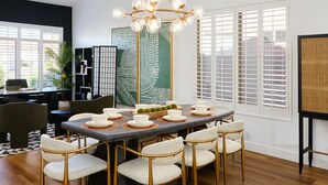A modern dining area with a round table, six chairs, and a chandelier.