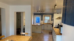A compact kitchen with white cabinets, a wooden dining table, and a view of the adjacent living area. - Bermuda House with parking, good sea view and minutes from beach and shops (Ventnor)