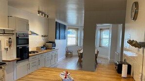 A modern kitchen with white cabinets, a wooden countertop, and a dining area with a table and chairs. - Bermuda House with parking, good sea view and minutes from beach and shops (Ventnor)