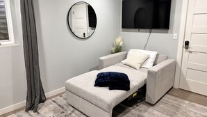 Een slaapkamer met een bed, een aan de muur bevestigde televisie en een deur.