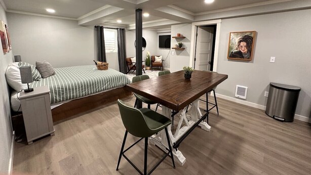 Een moderne, goed verlichte kamer met een bed, een bureau, een eettafel en stoelen.