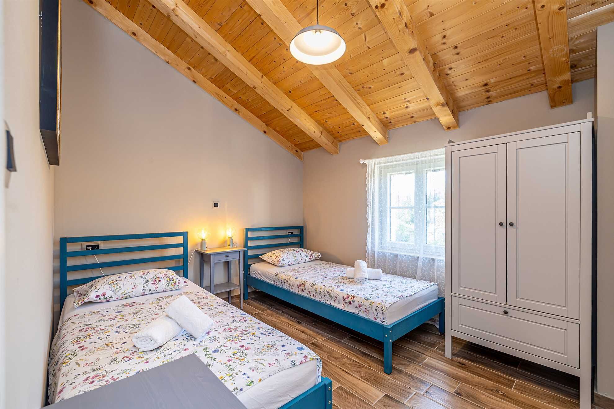 Un dormitorio con dos camas, un armario y una ventana.