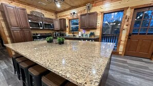 Cocina con encimeras de granito, armarios de madera y una isla grande con taburetes de bar.