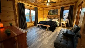 Un dormitorio de estilo cabaña, con cama, banco y sofá.