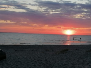 Une plage avec un coucher de soleil, une mer calme et un banc.