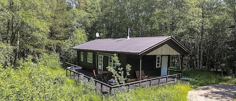 A cabin with a porch, surrounded by dense forest.