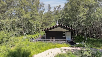 Uma cabana com varanda, cercada por uma floresta densa.