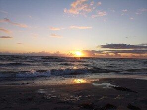 Une plage avec des vagues et un coucher de soleil.