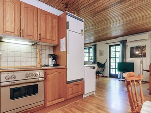 Une cuisine avec des meubles de rangement en bois, une cuisinière et un réfrigérateur.