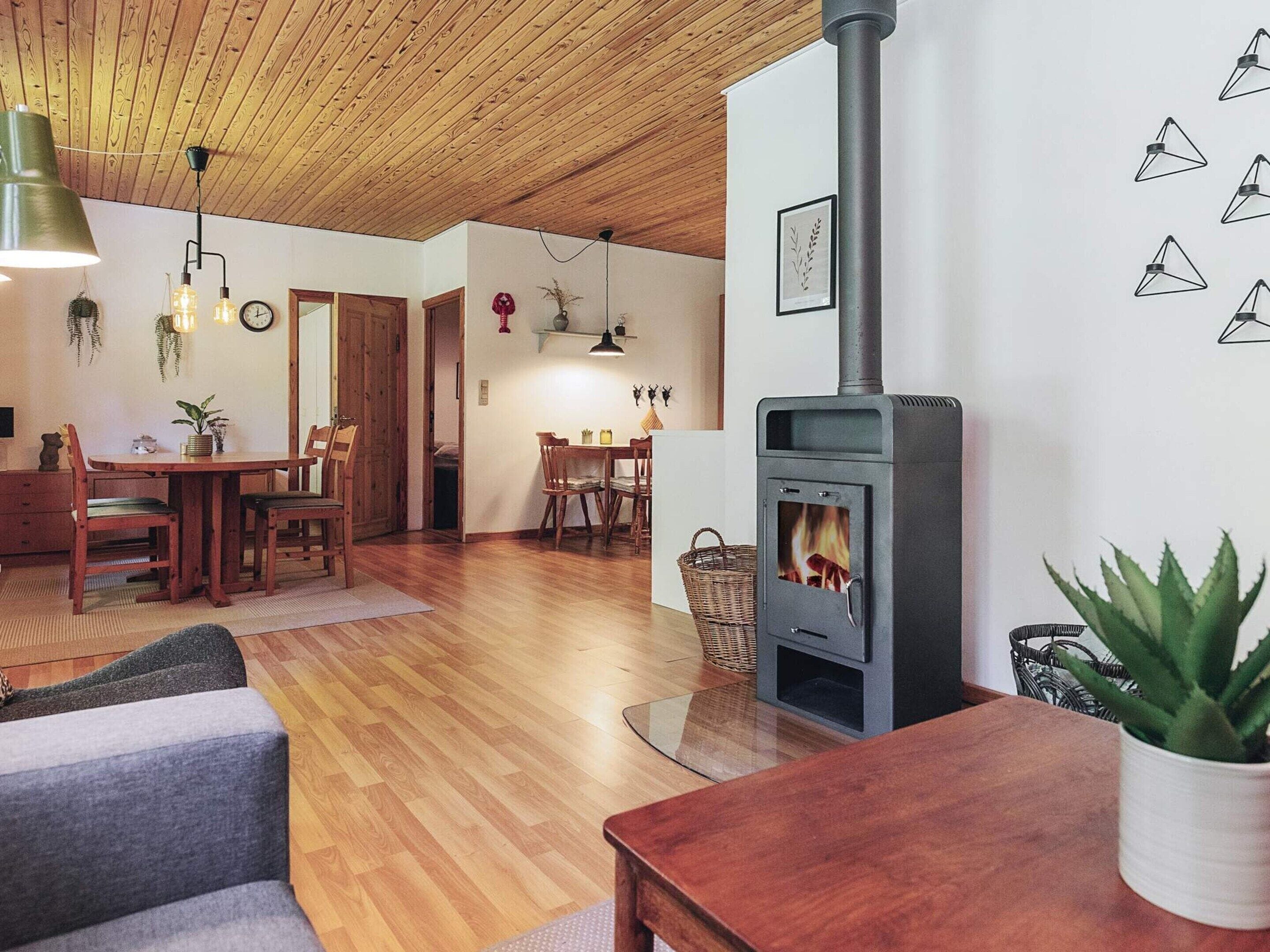 Een gezellige woonkamer met een houtkachel, houten meubels en een eethoek.