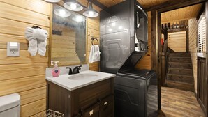 Un baño de estilo cabaña de madera con un lavabo blanco, armarios oscuros y un espejo grande.