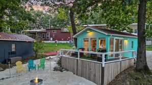 Une petite maison dotée d’une terrasse, d’un foyer extérieur et de meubles de jardin.