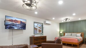 Une chambre à coucher avec un lit, une télévision, une commode et un canapé.