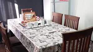 A dining table with a Paris-themed tablecloth, four wooden chairs, and a refrigerator in the background. - LODGING NAOMI VILLA UNIÓN PROVINCE OF LA RIOJA  (Villa Unión)