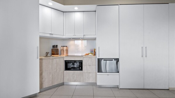 Una cocina moderna con armarios blancos, horno empotrado y microondas.