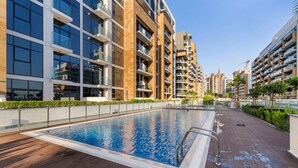 Un moderno edificio residencial con piscina en la azotea, rodeado de otros edificios de gran altura.