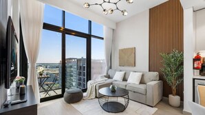 Una sala de estar moderna con un sofá, una mesa de centro y un ventanal con vistas a la ciudad.
