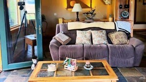 A living room with a purple sofa, a wooden coffee table, and a glass door leading outside. - Winter Dream Getaway (Kremmling)