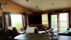 A wooden interior with a kitchen island, a ceiling fan, and a television. - Winter Dream Getaway (Kremmling)
