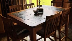 A wooden dining table with six chairs, a window with curtains, and a view of a green landscape. - Winter Dream Getaway (Kremmling)