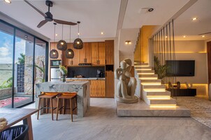 A modern kitchen with a central island, wooden cabinets, and pendant lighting.