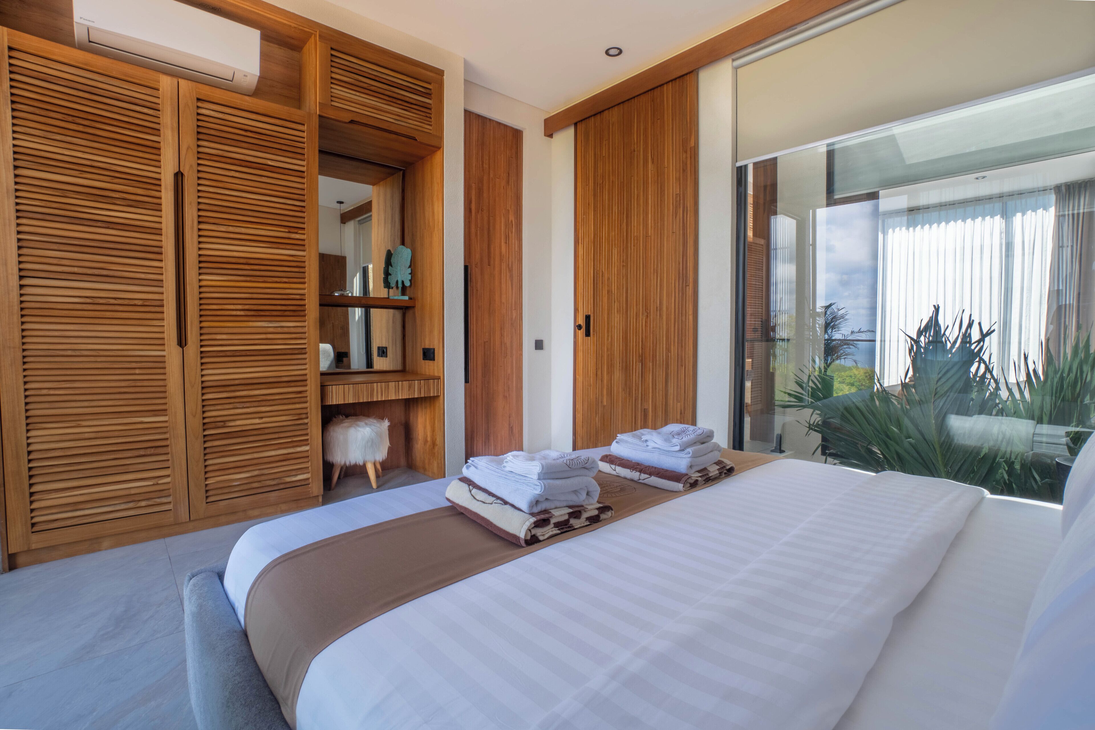 Un dormitorio moderno con una cama grande, un armario de madera y vistas a zonas verdes.