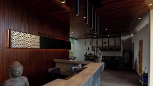 A reception area with a wooden wall, a Buddha statue, and a modern reception desk. - Rahya Villas Complex (Kutuh)