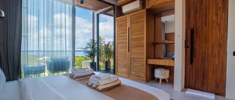 A modern bedroom with a large bed, a wooden wardrobe, and a balcony with a view.