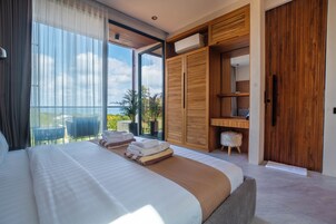 A modern bedroom with a large bed, a wooden wardrobe, and a balcony with a view.