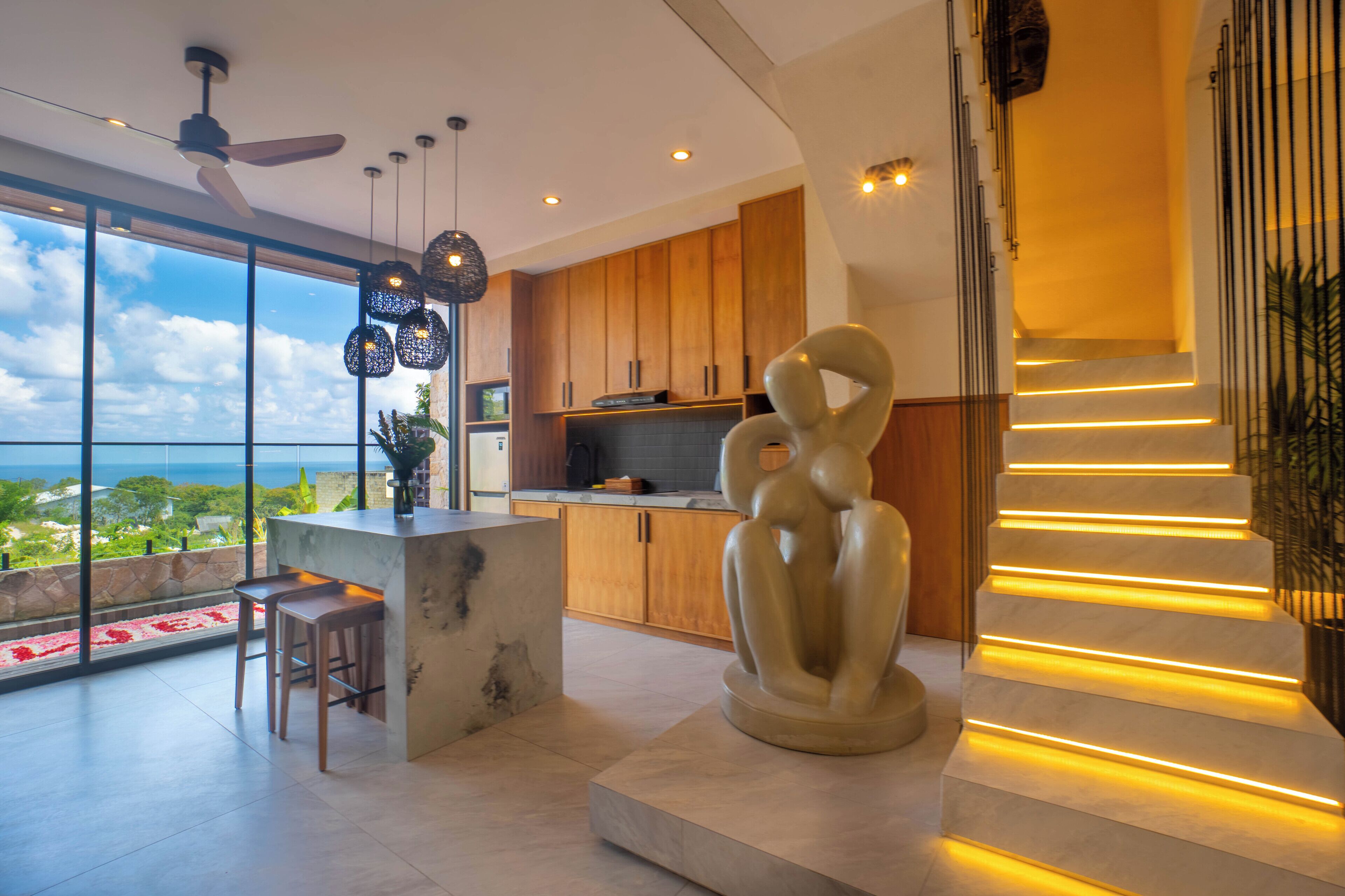A modern kitchen with wooden cabinets, a central island, and a large window overlooking a scenic view.