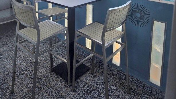A balcony with a table and chairs, overlooking the sea.