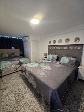 A hotel room with two beds, a patterned carpet, decorative wall art, and a ceiling light. - Oceanview 3-bedroom apartment with 4 beds in Condado!! (San Juan)