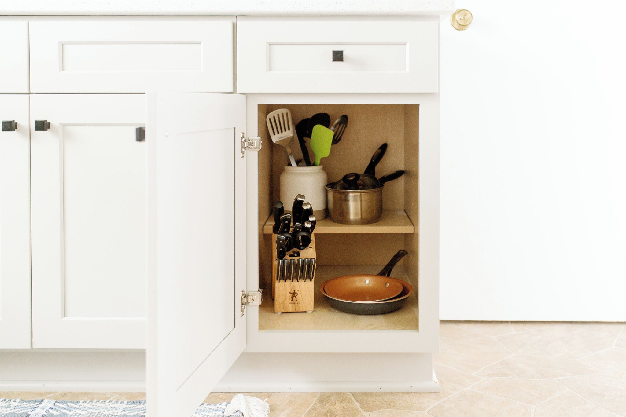 A kitchen cabinet with a built-in spice rack and utensil holder.