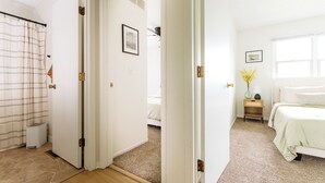 A bedroom with a bed, a nightstand, a lamp, and a window.