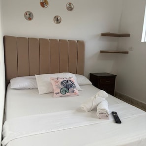 A neatly made bed with a pillow, a remote control, and a towel on a white mattress. - Hotel Colombia del Golfo (Tolú)