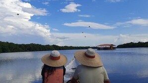 Two people in a boat with a water body and a distant structure. - Hotel Colombia del Golfo (Tolú)