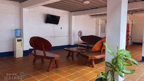 A room with wooden furniture, a television, and a water dispenser. - Hotel Colombia del Golfo (Tolú)