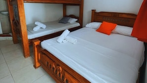 A room with a wooden bunk bed, a single bed with white bedding, and a red pillow. - Hotel Colombia del Golfo (Tolú)