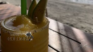 A tropical drink on a beach with a palm tree and ocean view. Text reads "Playas de Covena A 30 minutos HOTEL COLOMBIA". - Hotel Colombia del Golfo (Tolú)