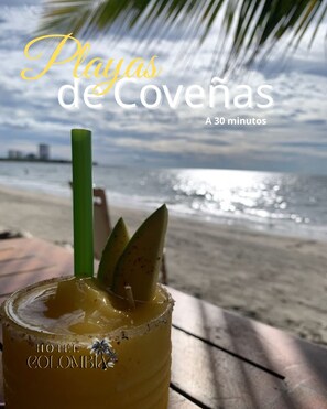 A tropical drink on a beach with a palm tree and ocean view. Text reads "Playas de Covena A 30 minutos HOTEL COLOMBIA". - Hotel Colombia del Golfo (Tolú)
